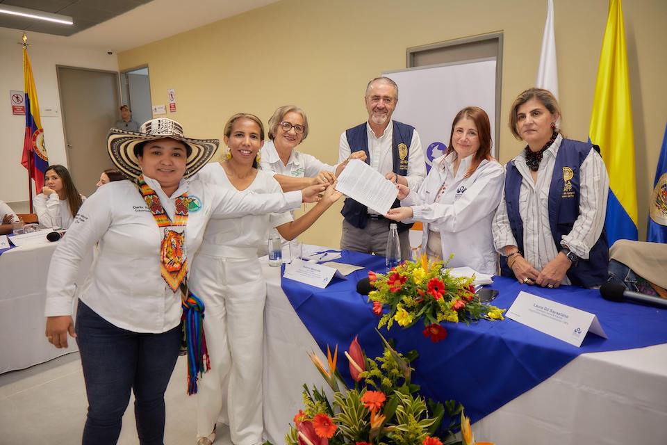 Defensora muestra documento junto a otras personas