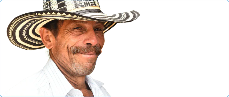 Hombre mayor sonriente con sombrero vueltiao y camisa blanca.