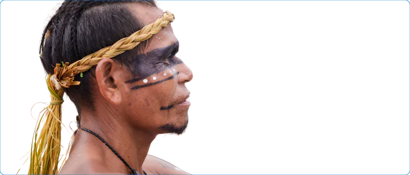 Hombre indígena de perfil, con corona de fibra trenzada y pintura facial negra y blanca.
