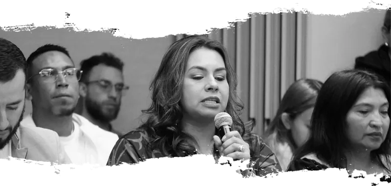 Una mujer interviene con micrófono durante una sesión de la Mesa Nacional de Garantías, rodeada de otras personas asistentes.